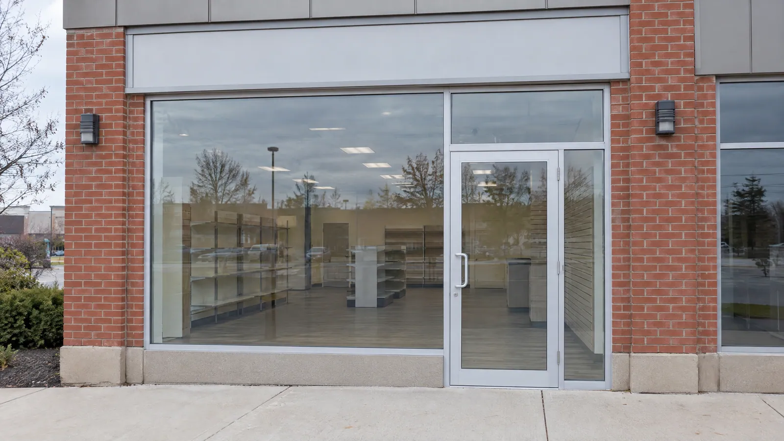 Empty retail unit with an aluminum storefront: a large display window, a glass transom above and a glass entry door